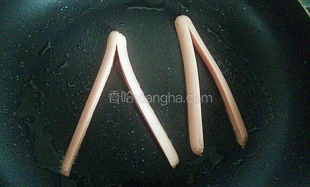 平底锅烧热，刷上一层油，放入火腿肠