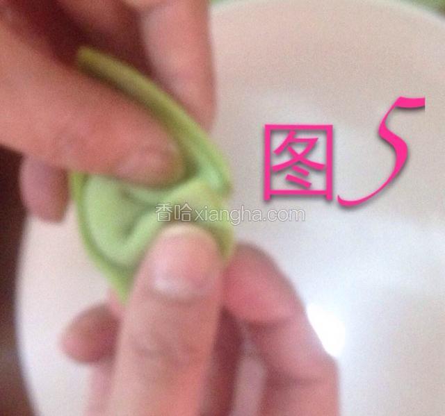 如图所示。
左手在下。右手在上。把两头压住（这个时候在馄饨皮上稍微摸一点水、这样容易粘住）煮的时候不会散开。