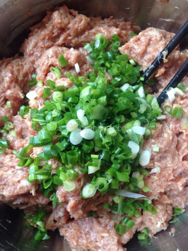 如图所示：搅拌均匀的肉馅加入葱花和少许麻油，再一起搅拌均匀
