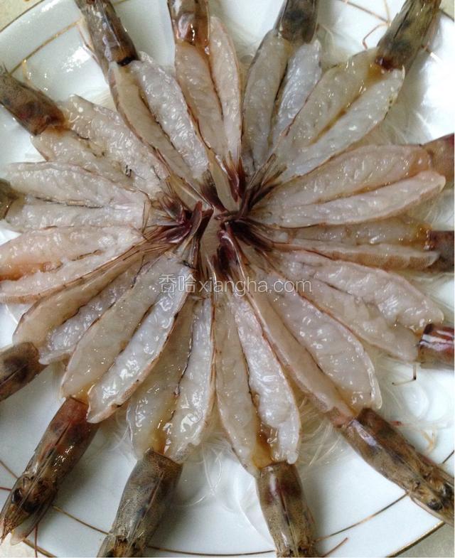 把开好背的大虾整齐的铺在粉丝上放好。
虾头对外，虾尾聚在中间。