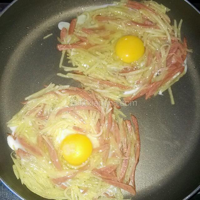 鸡蛋打入碗中，用汤勺将蛋黄倒入中间的小洞中，蛋白均匀的淋在土豆火腿丝上面，煎至底面微焦