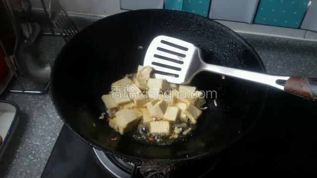 下入豆腐块和盐煸炒几分钟，使豆腐在煸炒时入咸味