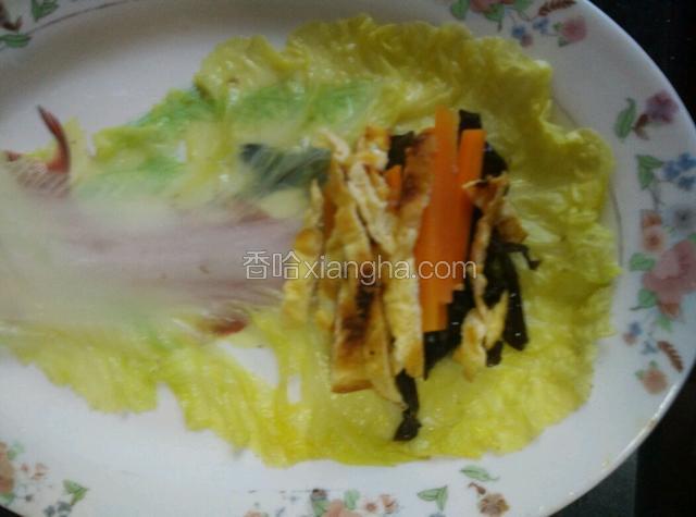白菜叶平铺，放适量的胡萝卜、木耳、鸡蛋丝，卷起