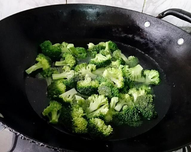 锅中烧沸水，淋入花生油，倒入西兰花，加入两勺子盐盖上盖子焯1分钟水