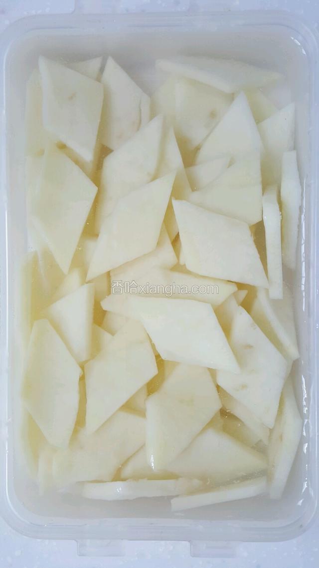 土豆一切两半，斜切使截面成菱形，切菱形片，用清水浸泡