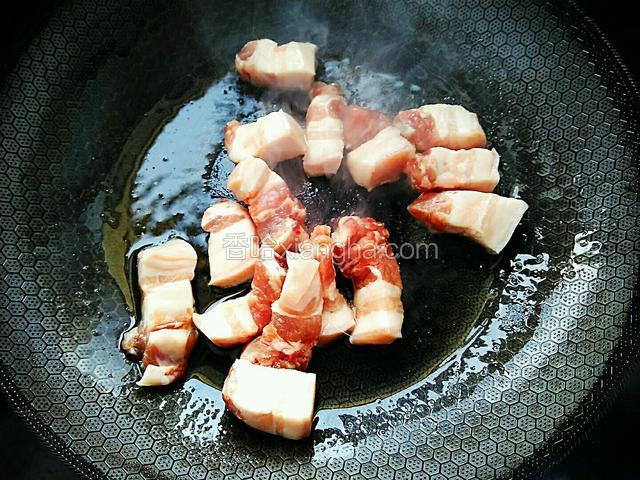 油热后撇去姜丝。倒入处理过的五花肉。不停的翻炒锅里的五花肉，使每块肉都均匀的裹上油。