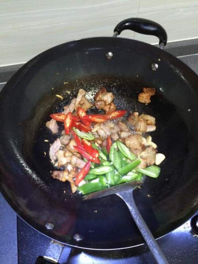 瘦肉变色后，接着加入适量盐调味，倒入辣椒块一起炒。