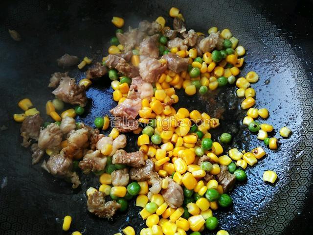 牛腩炒出香味，加玉米粒和豌豆粒一起翻炒均匀。