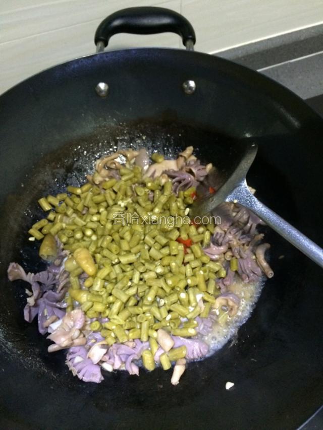 紧接着倒入酸豆角炒匀。