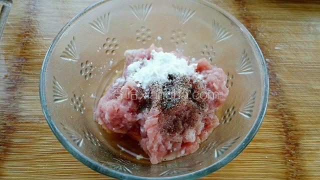 肉糜中加入料酒、黑胡椒粉和少许淀粉，抓拌均匀腌制十分钟。