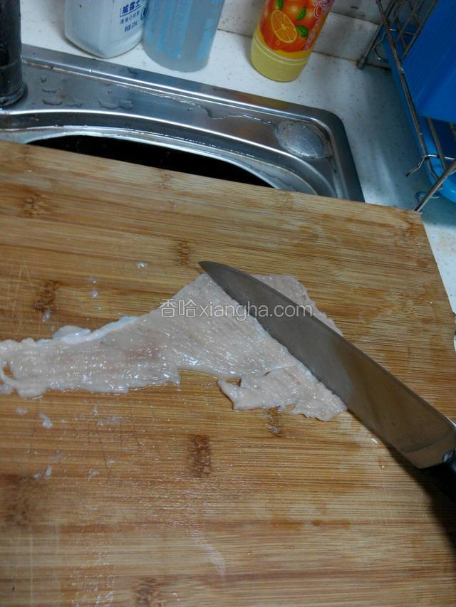把鸡脯肉放在砧板上用刀背轻轻的敲打一面，再翻过来敲打另一面，两面都敲打一会放入容器里。