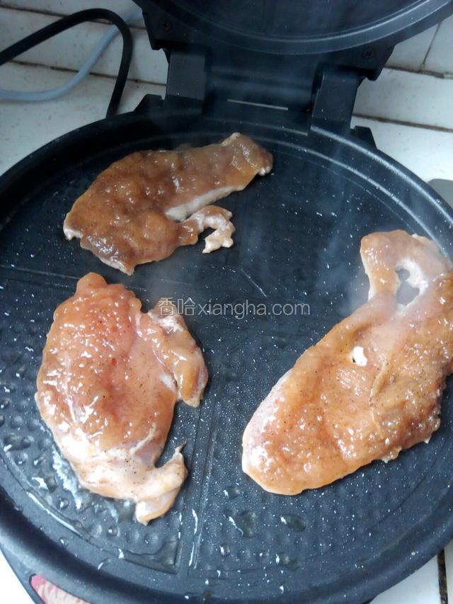 把腌制好的鸡脯肉放在加热了的电饼档里煎制，电饼铛里要先少量刷一层油。
