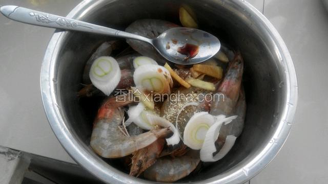 把虾放入盆中，放进葱花和姜片，再倒入两勺料酒，一勺生抽，少许盐和鸡精拌匀后腌制二十分钟，中途要翻一翻。