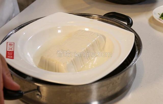 把豆腐从蒸锅取出，控去多余的水分。