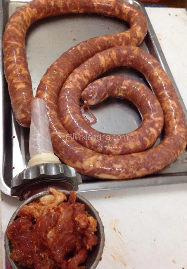 把腌制好的肉放入绞肉机，转动绞肉机，把肉送进肠衣里。
如图所示～(刚开始把肉送到肠衣头部的时候，需要把肠衣里的空气排掉，然后用绳子系紧了。
后面灌的时候也要尽量排空肠衣里的空气，特别需要注意的是，不要把肠衣塞的太满了，需要留一点点余地，因为一会还要把灌好的香肠，分成小段用绳子系起来。系绳子的地方需要提前预留，不然香肠会爆开。)