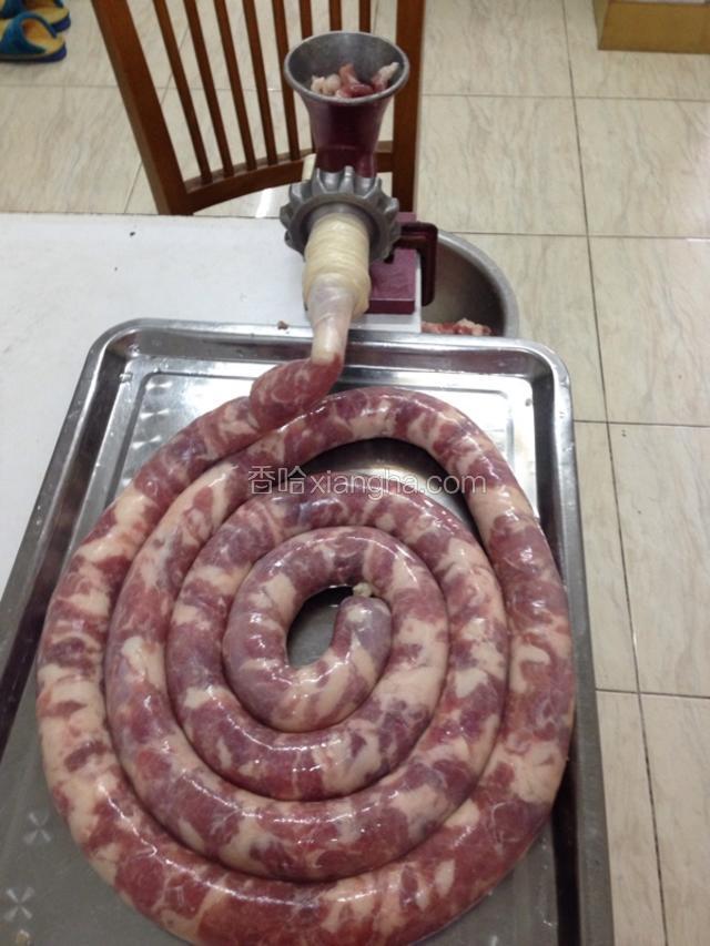 把腌制好的肉放入绞肉机，转动绞肉机，把肉送进肠衣里。
如图所示～(刚开始把肉送到肠衣头部的时候，需要把肠衣里的空气排掉，然后用绳子系紧了。

后面灌的时候也要尽量排空肠衣里的空气，特别需要注意的是，不要把肠衣塞的太满了，需要留一点点余地，因为一会还要把灌好的香肠，分成小段用绳子系起来。系绳子的地方需要提前预留空间，不然香肠会爆开。)