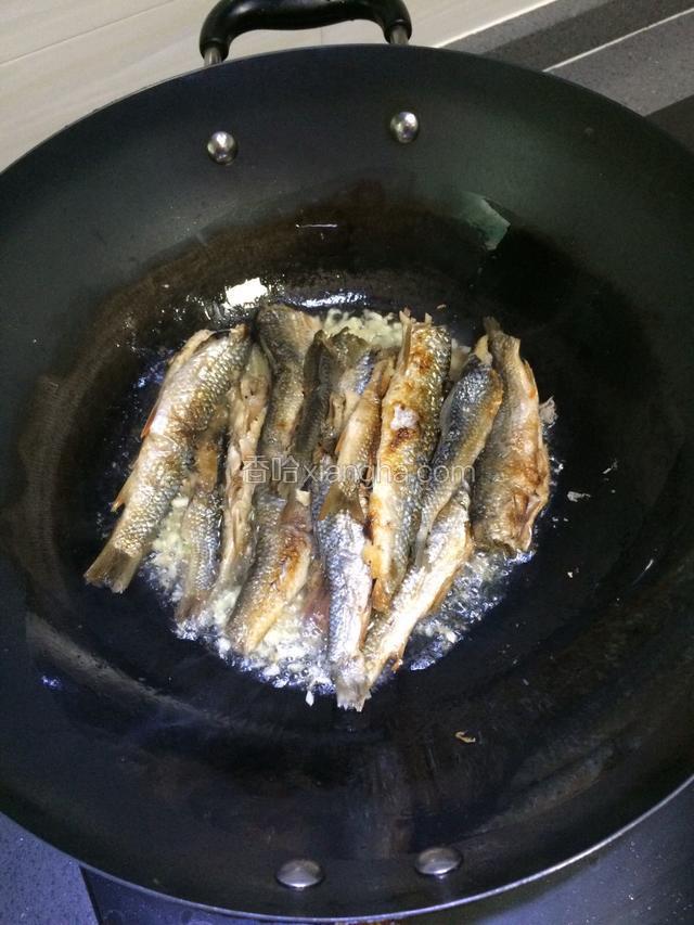 姜蒜爆香后，倒入鱼干下锅一起煎香一下。一分钟左右。