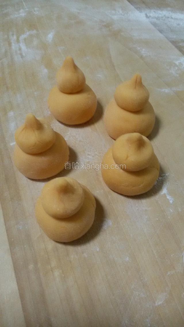 大小面团都揉成圆形，一个小面团放在一个大面团上，小面团顶部捏出小尖