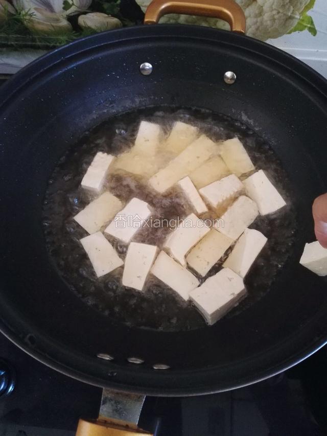 油锅烧热，把豆腐块用厨房纸擦干水，沿锅边慢慢丟进锅里，主要是防下油锅时溢溅。