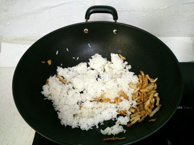 用锅铲把腊肉铲至一旁，(小火)倒入米饭弄散再炒匀。