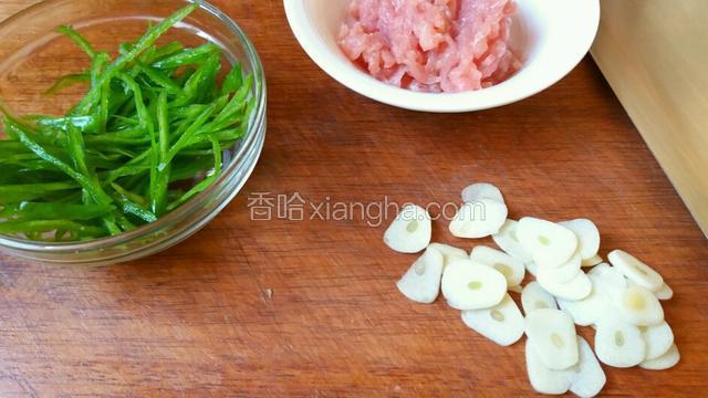 青椒去筋、籽切成细丝，和土豆丝差不多粗细。蒜横着切成薄片。
