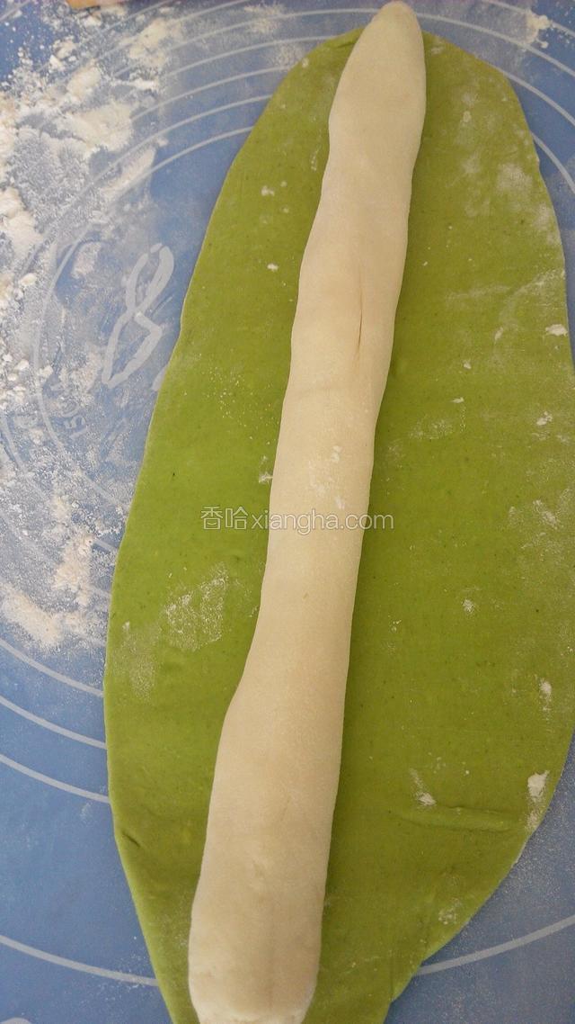 把一块白面团揉匀，搓成长条，用菠菜面片包住