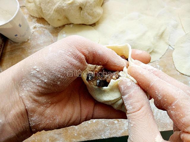一边用左手拇指往中央按压馅料，一边用右手拇指和食指沿四周边缘捏褶子