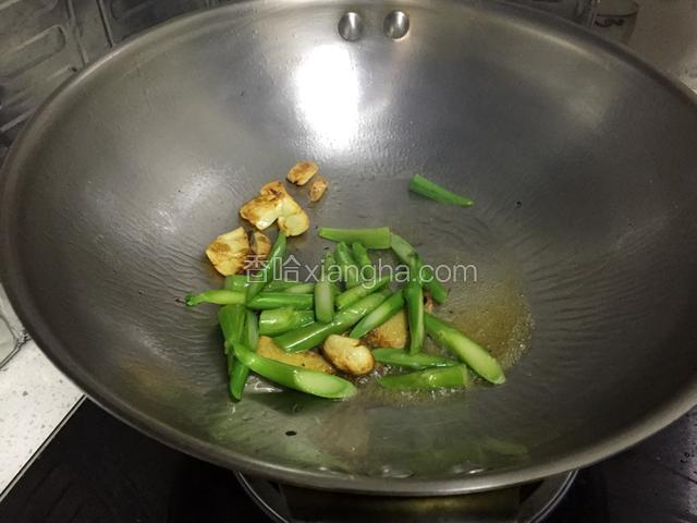 然后加入芥蓝茎部翻炒，将姜蒜挑出来弃之不用