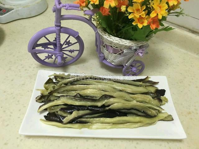 待蒸熟的茄子放凉，用手撕成长条码盘。