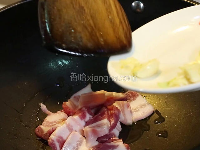 锅中再放油10克，油热七成。中火把五花肉煸香，把蒜子倒入炒香。
