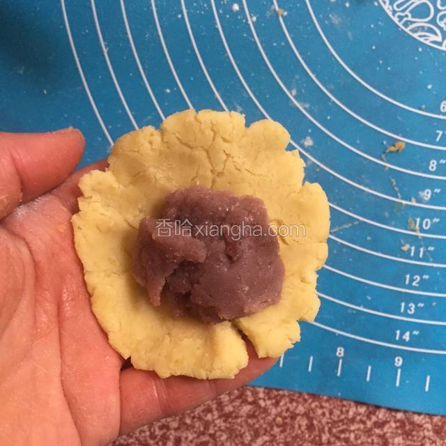 这时来做包馅料的，把30克的小面团揉圆后按扁，包上红豆馅，