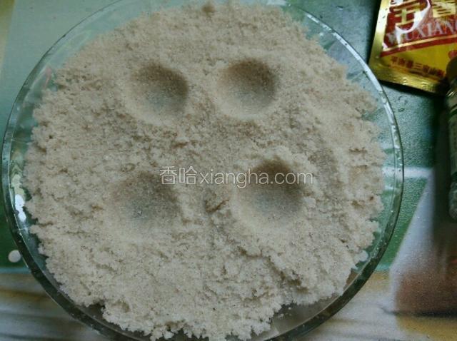 为了让这个蛋黄好成型，在盐里倒少许水搅拌成湿盐。拿一个鸡蛋，用比较尖的一头在湿盐上按几个坑。
