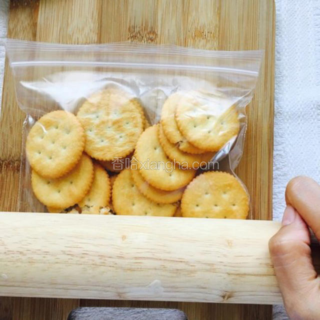 把饼干放入一个封口袋子里，然后用擀面杖来回压碎