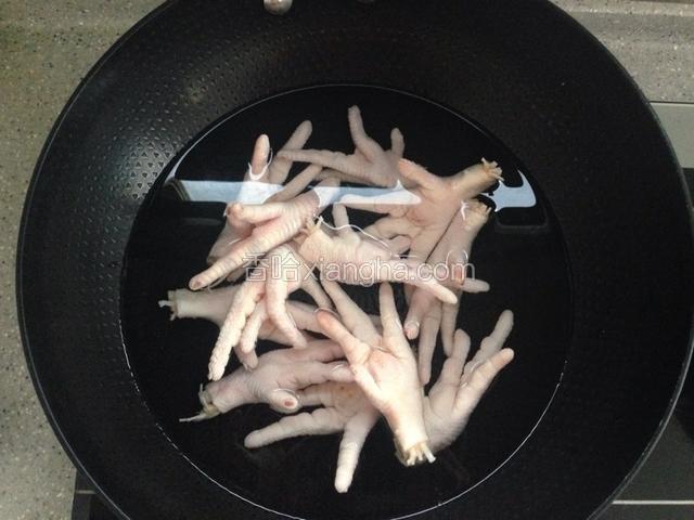 锅里放水，倒入鸡爪和料酒，大火煮十分钟。这个时间把大蒜切末