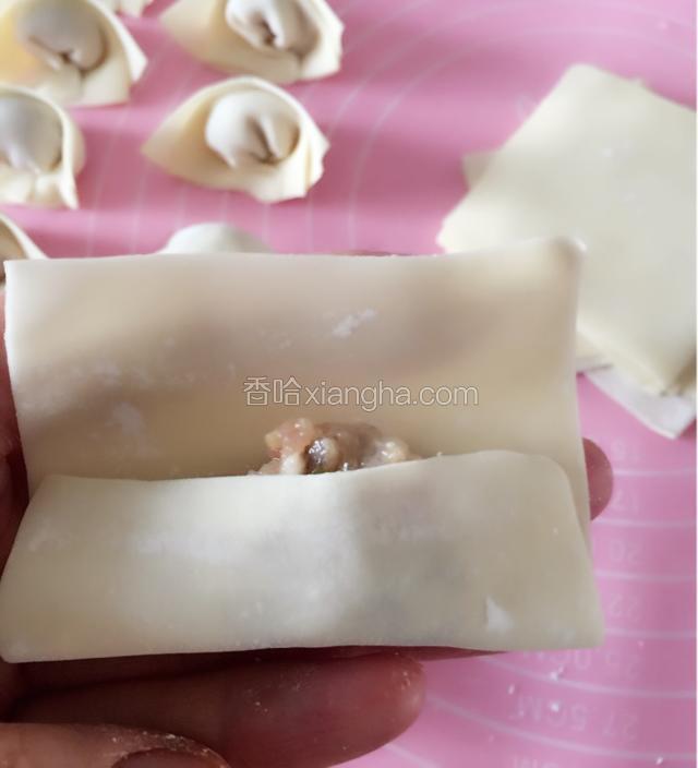 取一枚馄饨皮，在皮中间放入适量馅料，先折起四分之一皮。