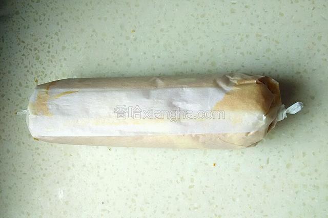用原来的油纸像包糖果一样把蛋糕卷包住，放冰箱冷藏半小时定型。不着急吃的话最好冷藏半天。