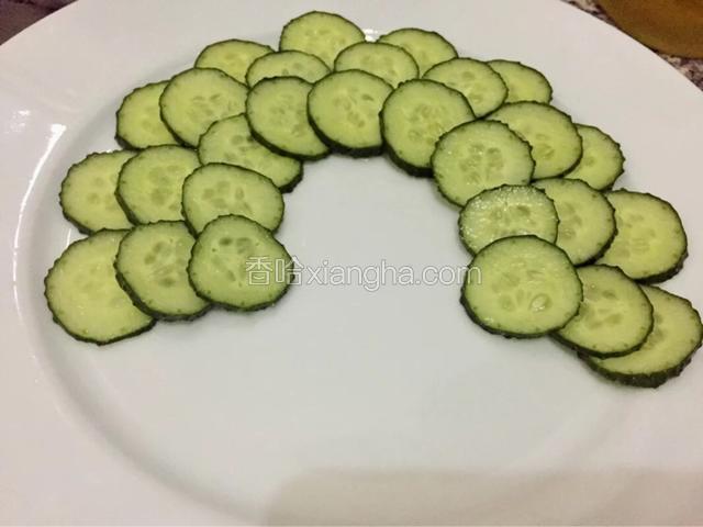黄瓜片一个挨着一个摆在盘子边缘，第二层压着第一层错开摆好，以此类推
