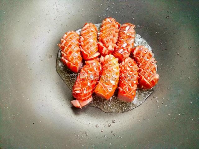 把切好的脆皮肠。用筷子放入油锅慢慢煎炸。晃动锅使脆皮肠受热均匀。