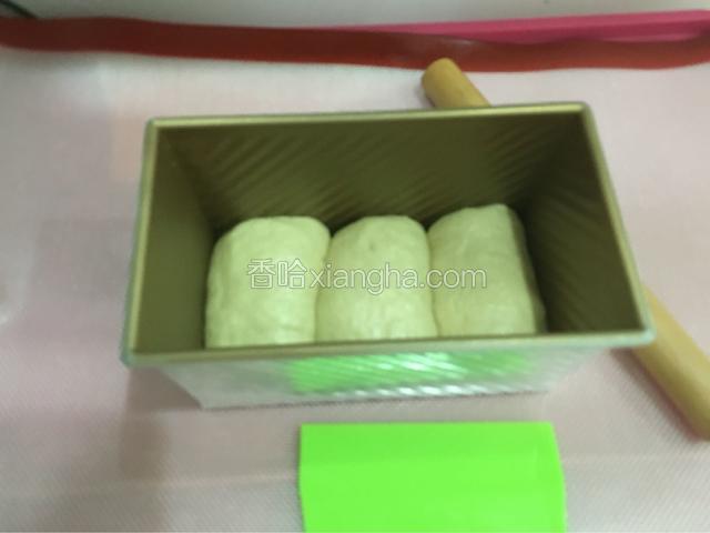 取出面团分成三份，用擀面杖擀成鸭舌状然后卷起放进吐司盒
