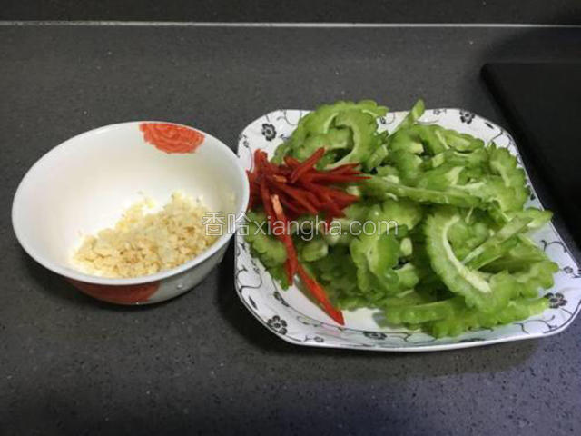 苦瓜对半切开，去掉苦瓜瓤，再切成均匀的薄片。
蒜切末，红椒切丝备用。