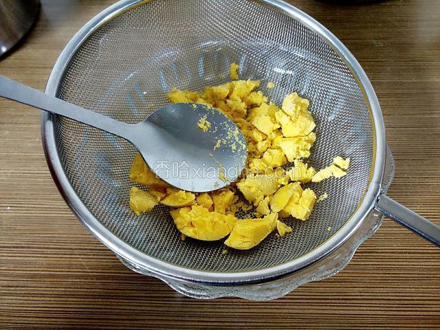 鸡蛋黄用勺背在漏网上碾压过筛。