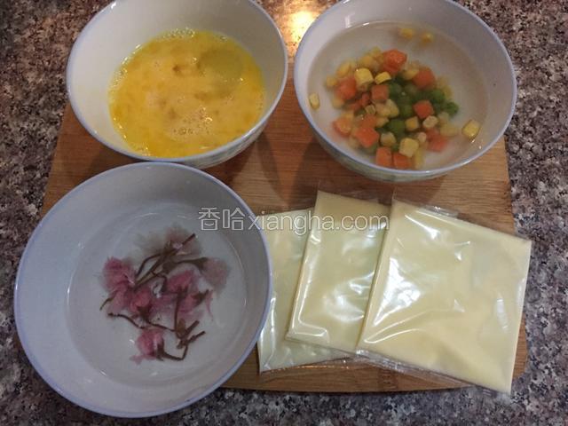 准备材料：盐渍樱花用冷水浸泡开，用筷子搅拌至盛开，芝士片一分为四，鸡蛋打散，什锦蔬菜丁备用

