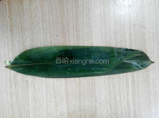把粽叶平铺到桌子上，两张叠在一起，头冲外，粽叶上面的沟一定要冲上，两张粽叶可以错开一点，这样能装多一点馅料