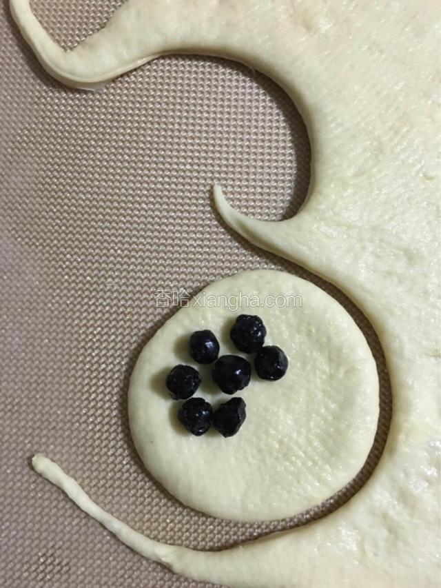 用直径8厘米的圆形饼干模或直径相同的玻璃杯口，压成小圆片，放上几个蔓越梅干；