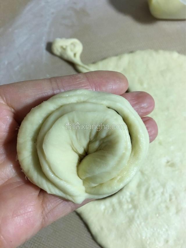 绕一圈后，捏紧两个头，像一个大馄饨的形状，放入烤盘中；