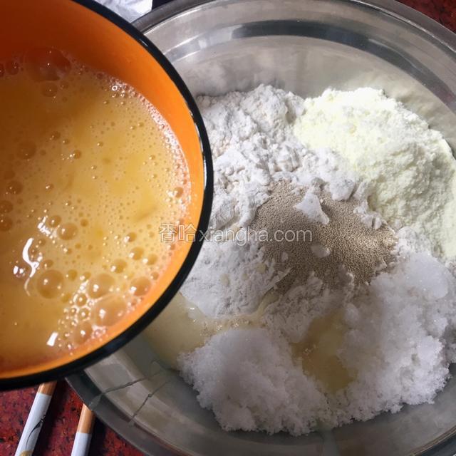 在面粉里加入酵母、糖、盐、奶粉、炼乳和鸡蛋用筷子搅拌