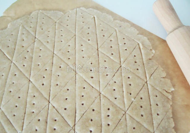 此时预热烤箱，上下火160度。然后将面团包上保鲜膜，擀成大约4mm薄，用刀子成三角形，再拿叉子在上面扎一下，造型就完成了。