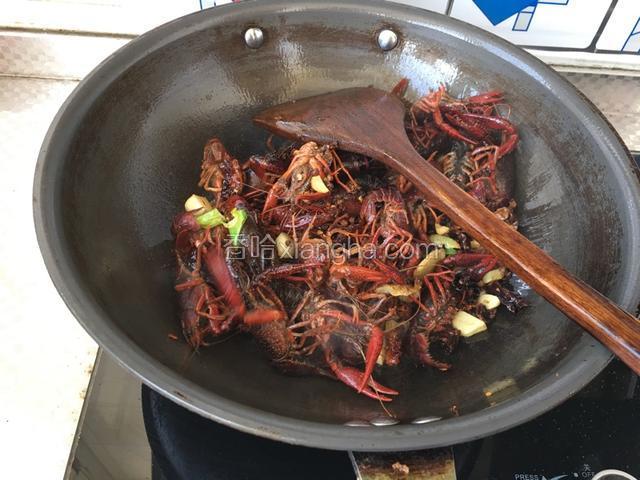 放小龙虾，放入少量料酒翻炒，加入胡椒粉，白糖，酱油调色，翻炒3分钟 加入少量水焖上盖子小火至汤汁浓稠