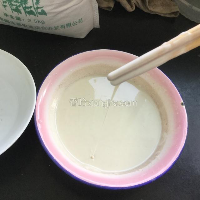 直到加水调成把筷子提起来，面糊能流成一条线而不断即可！要把面糊中的小疙瘩都搅开。