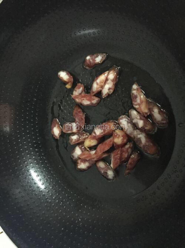 锅中倒入适量的油烧热后倒入腊肠，炒至腊肠变透明